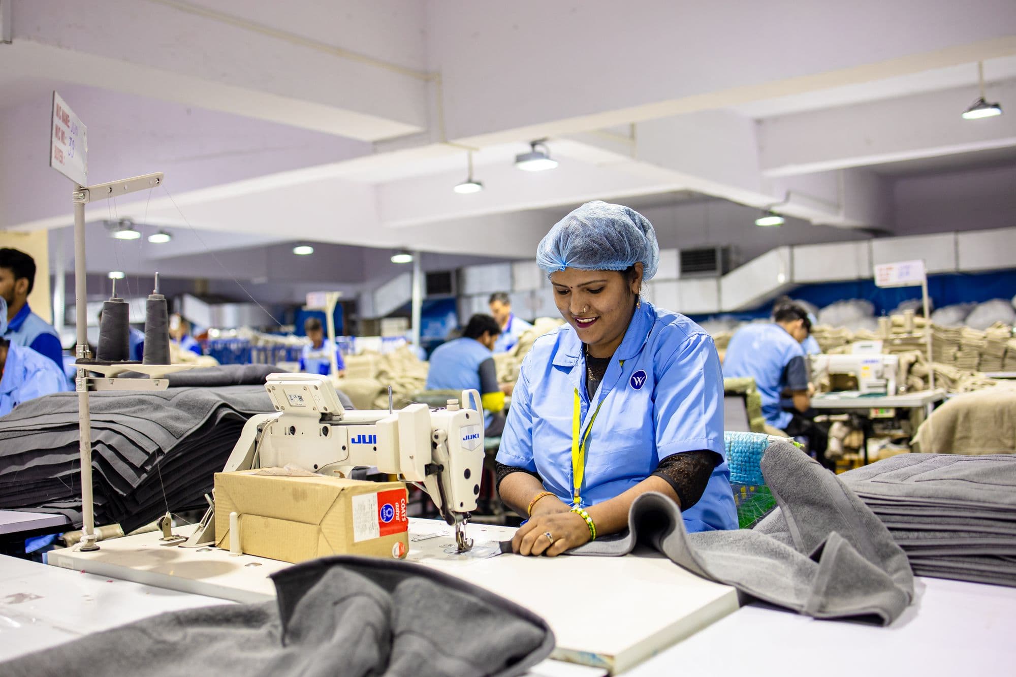 A garment worker at her sewing machine on a factory floor