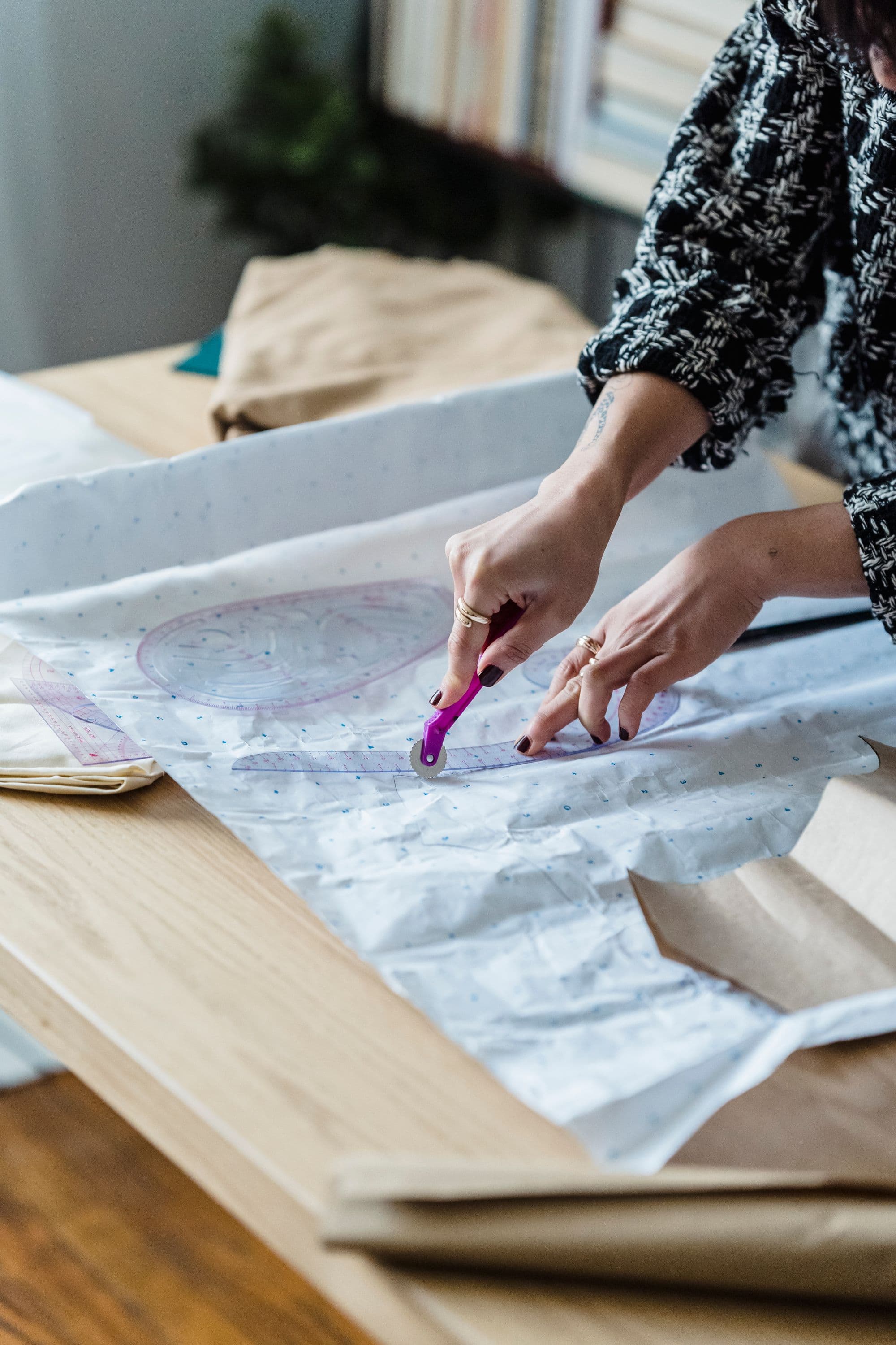 A pattern maker cutting a paper pattern with a ruler