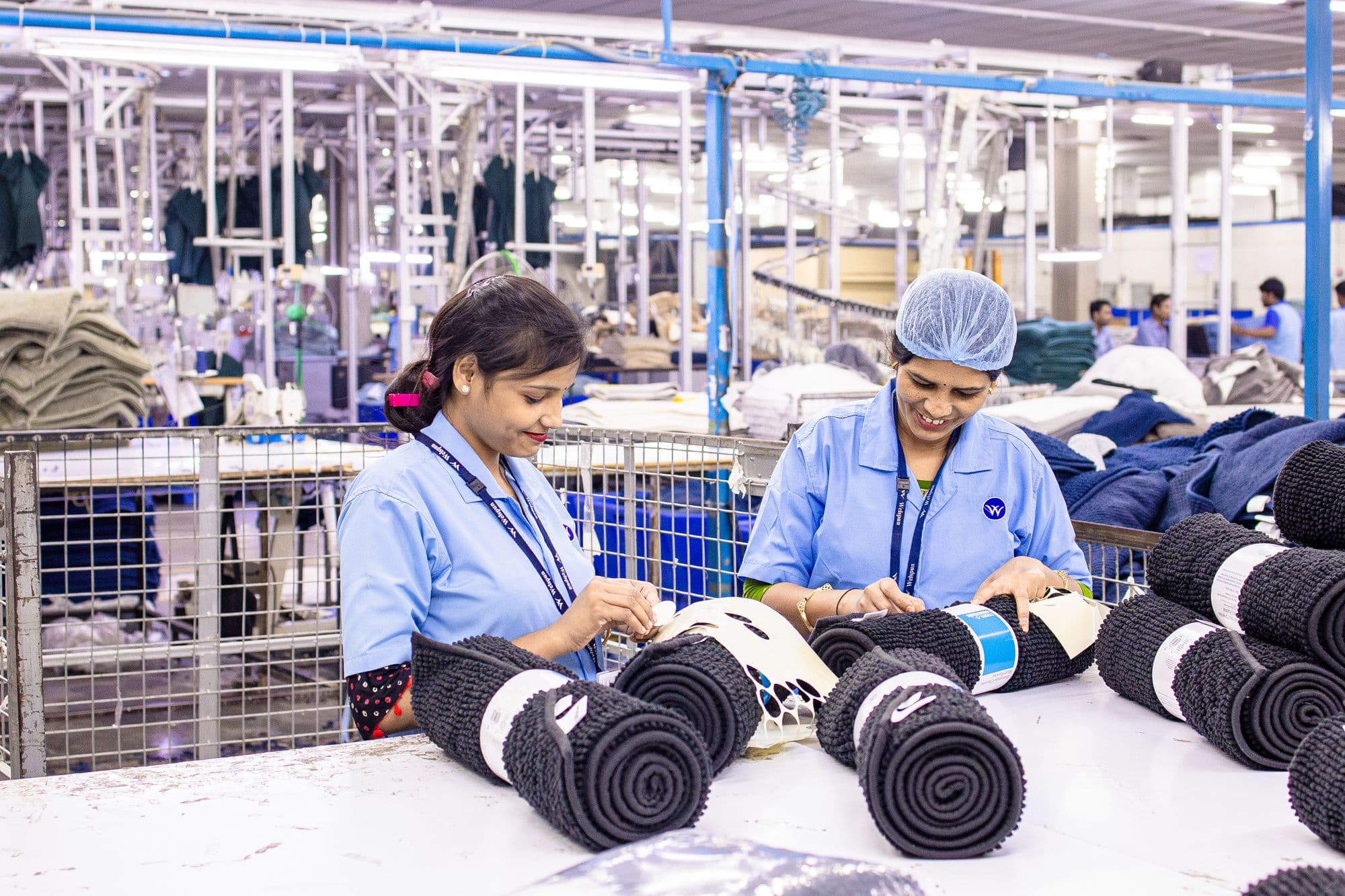 Two workers checking and rolling finished garments